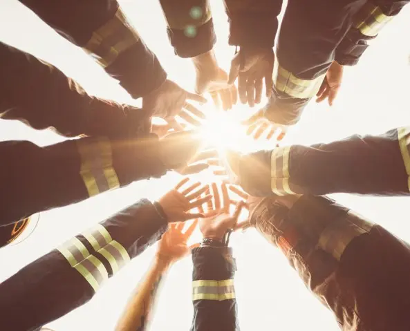 Bilde av en sirkel av mennesker der armer og hender strekker seg mot midten